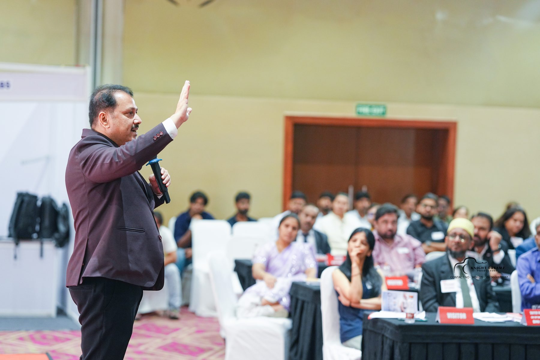 Uday Shetty speaking to attendees, hand raised